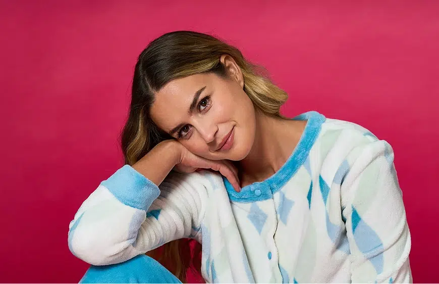 Ragazza con pigiama che sorride con viso appoggiato sulla mano