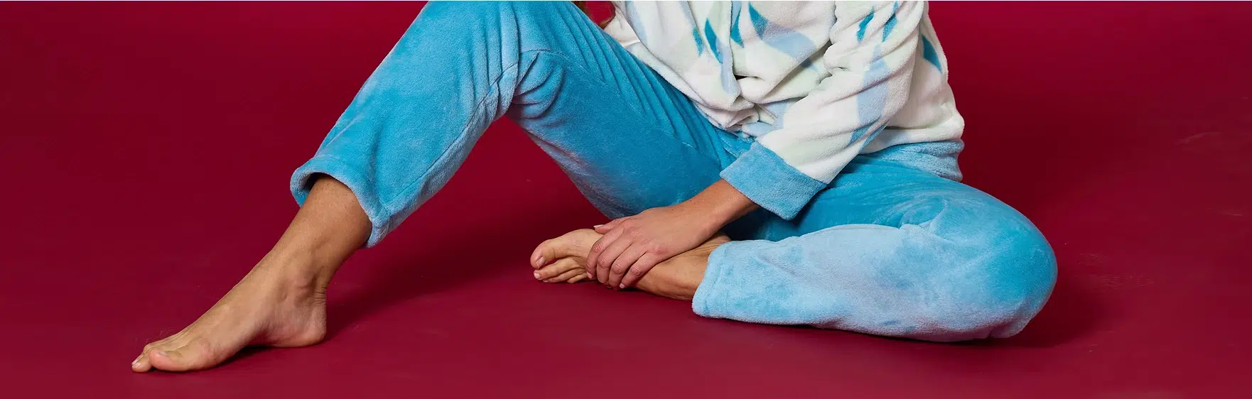 Gambe di una ragazza con pantaloni azzurri seduta su sfondo rosso