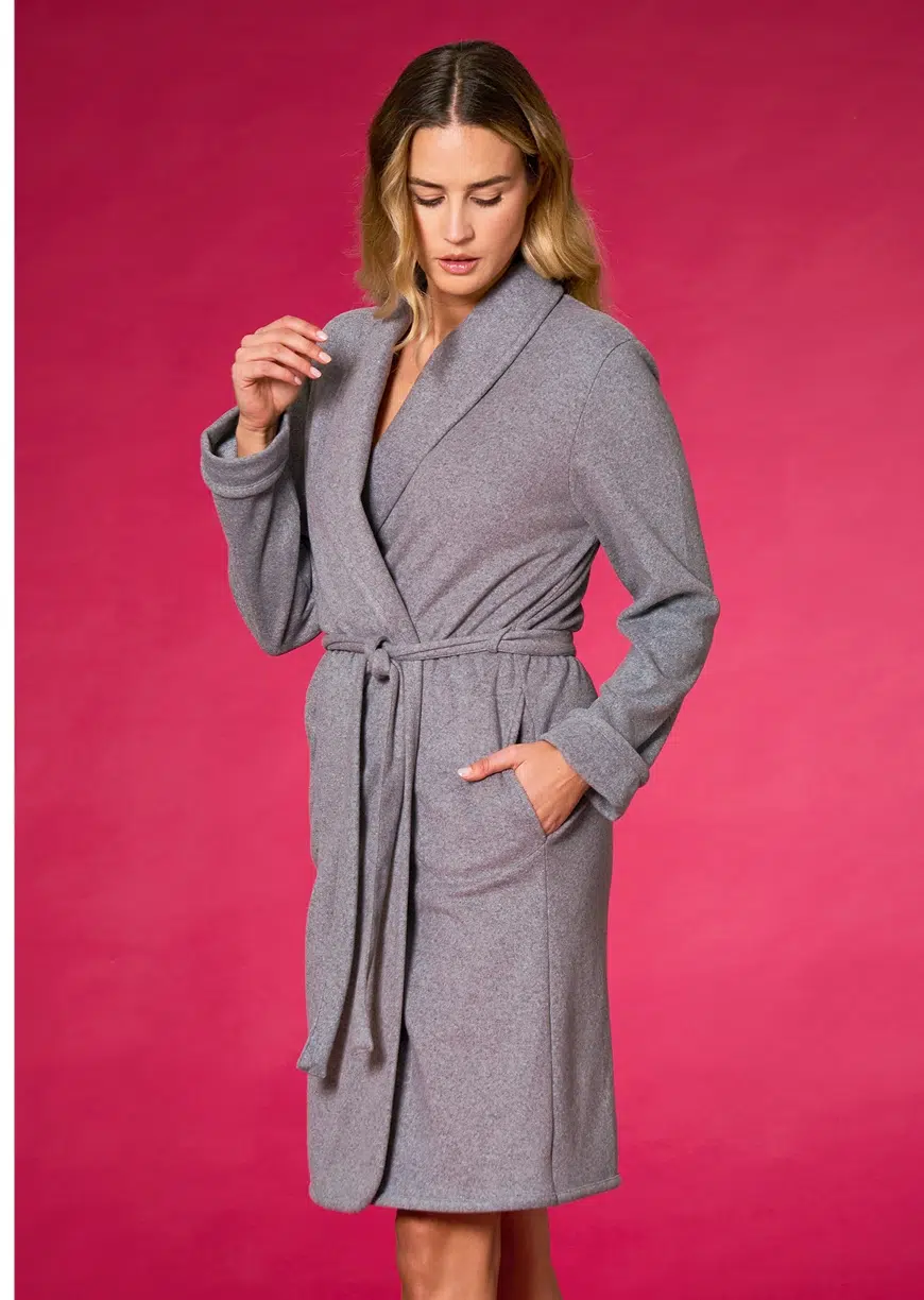 Ragazza con cappotto grigio che guarda in basso con una mano in tasca